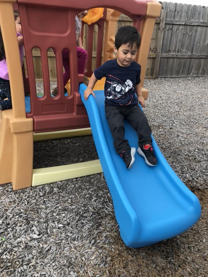 Child sliding down a blue slide on a playground
