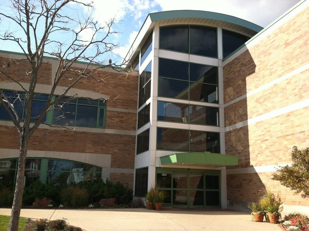 Brick building with a large glass entrance and a green awning