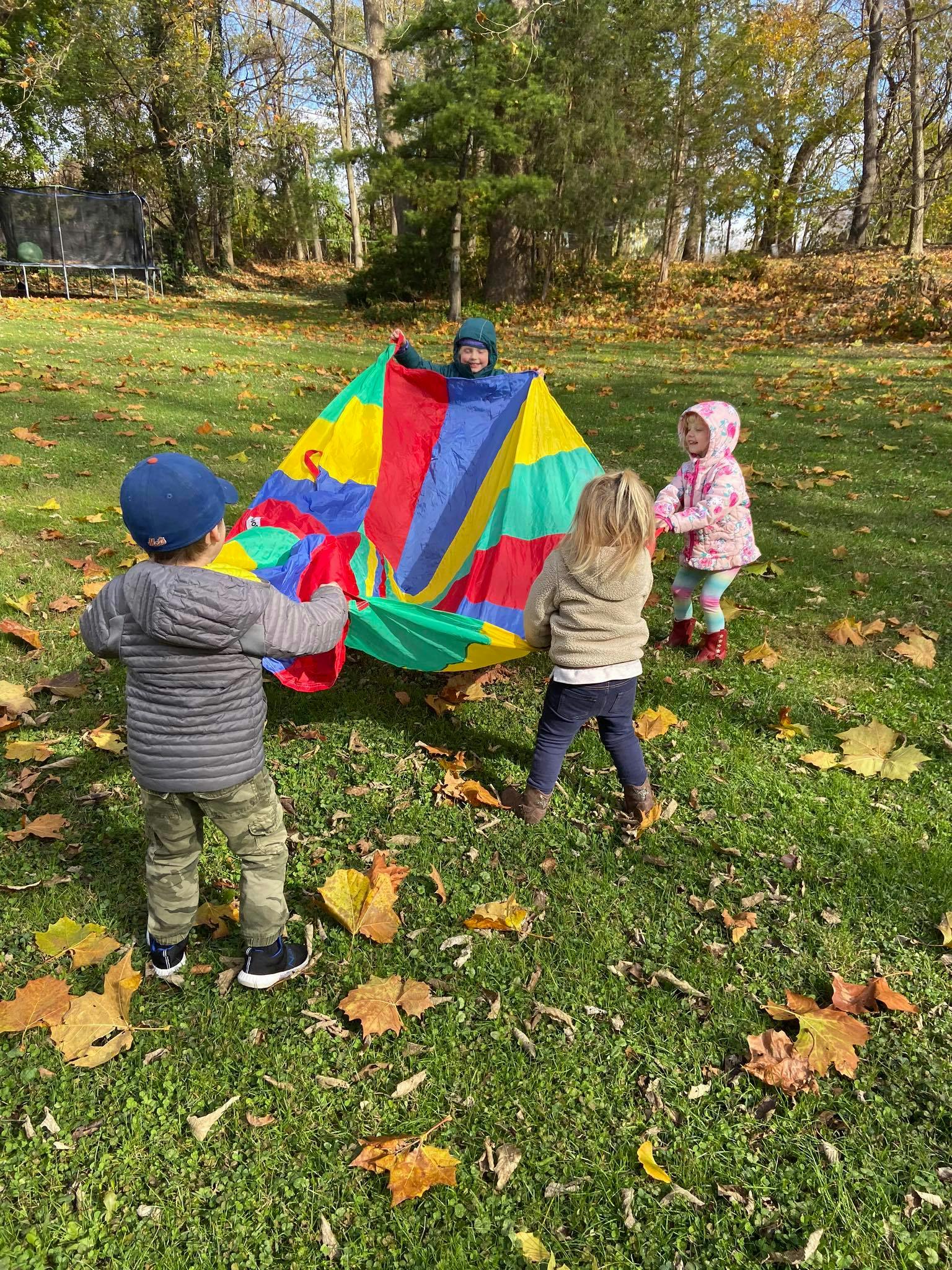 Children playing with a colorful parachute outdoors
