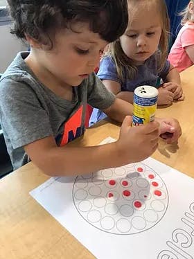 Child using a stamper on a paper with circles