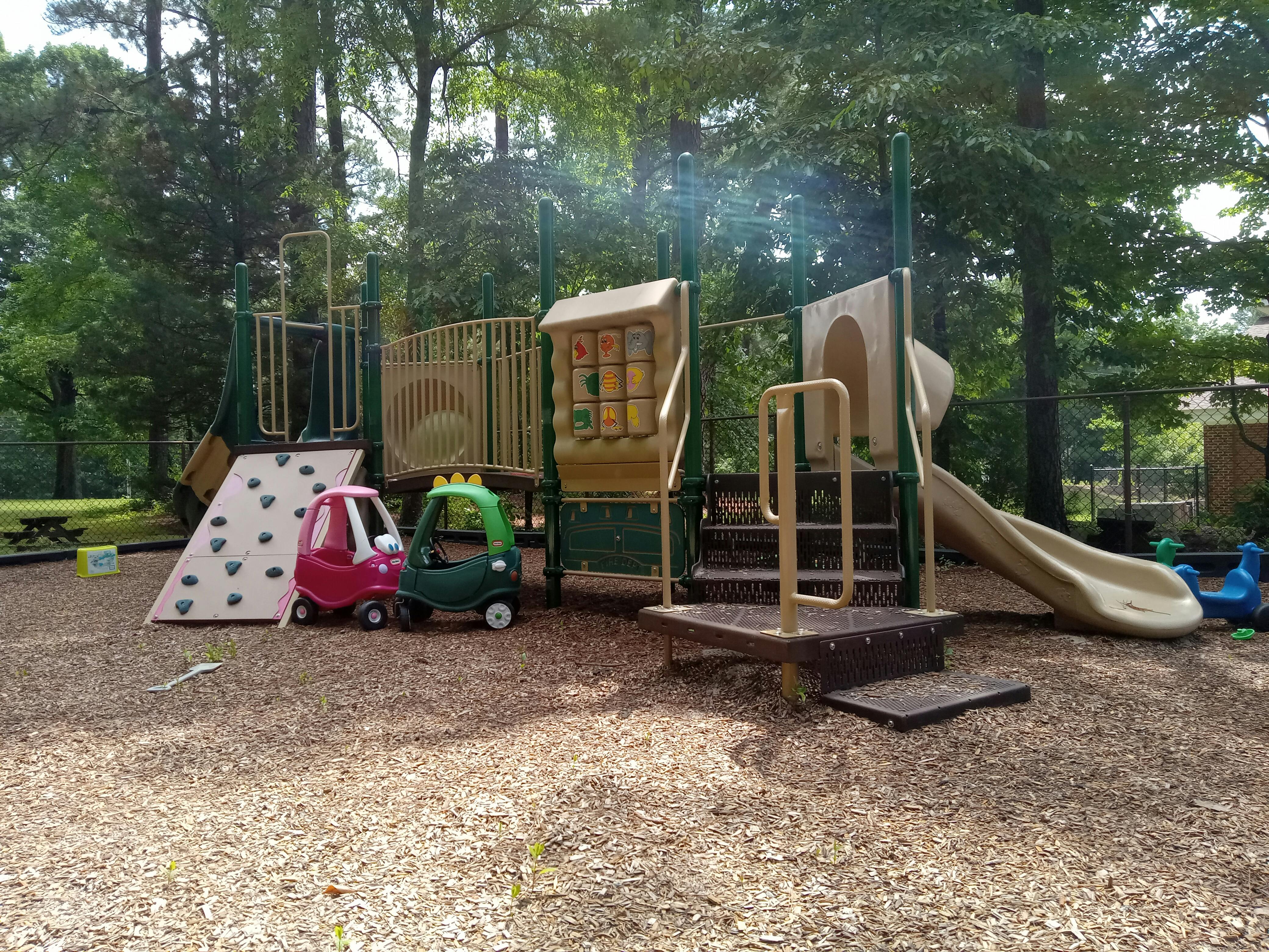 Playground with slides, climbing wall, and two toy cars