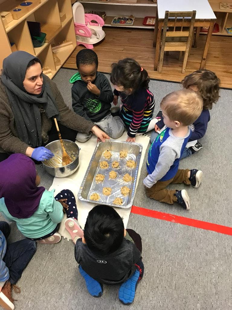 Adult and children making cookies in a classroom
