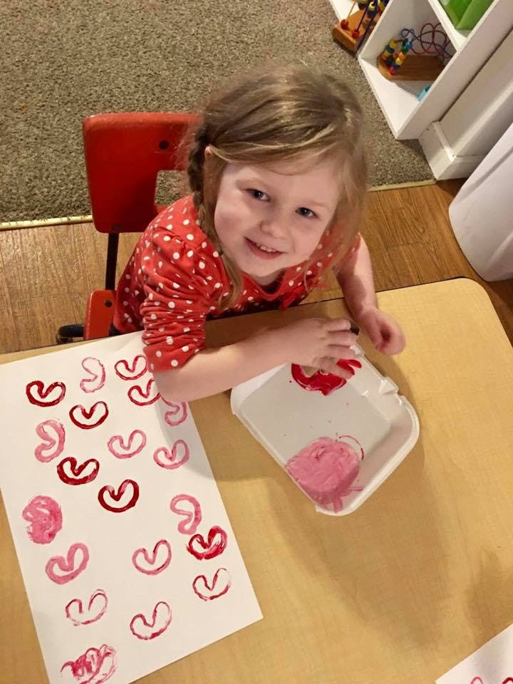 Child making heart prints on paper with paint