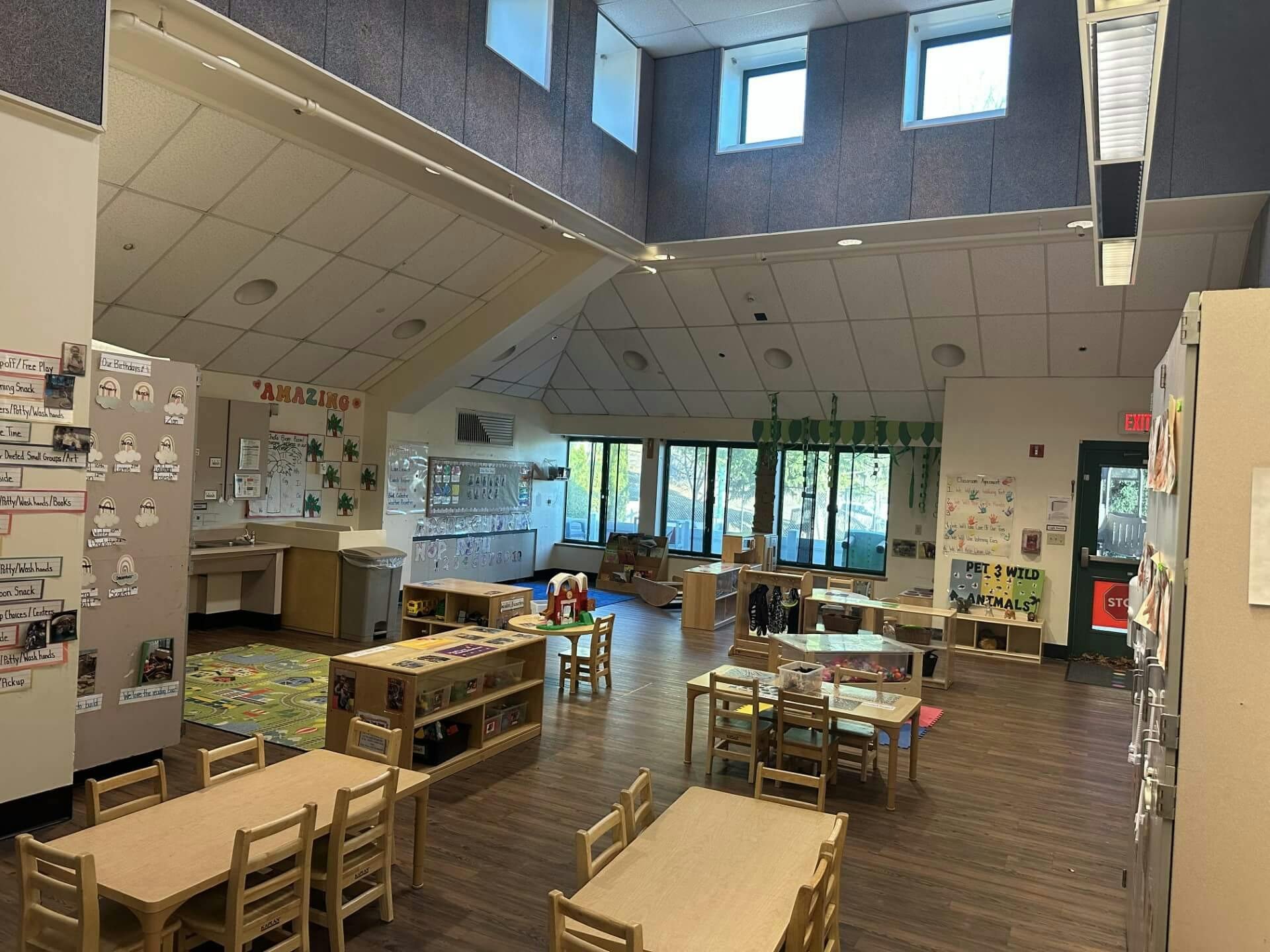 Classroom with small tables and chairs, shelves, and educational decorations