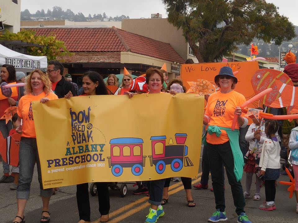 People holding a banner for Albany Preschool with a train graphic