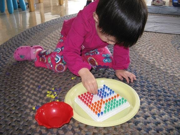 Child playing with a pegboard game on the floor