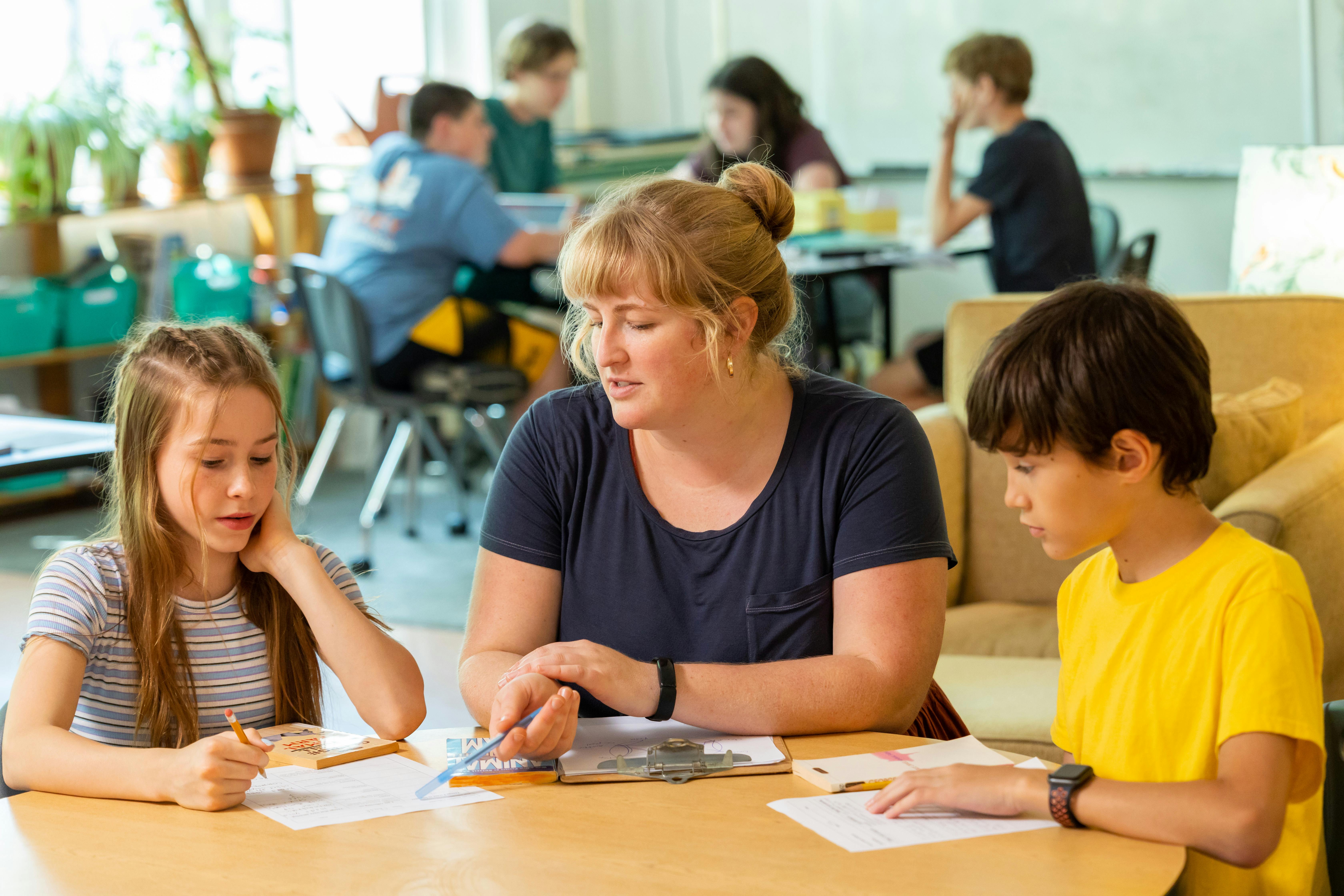 Adult and two children at a table with papers and pencils