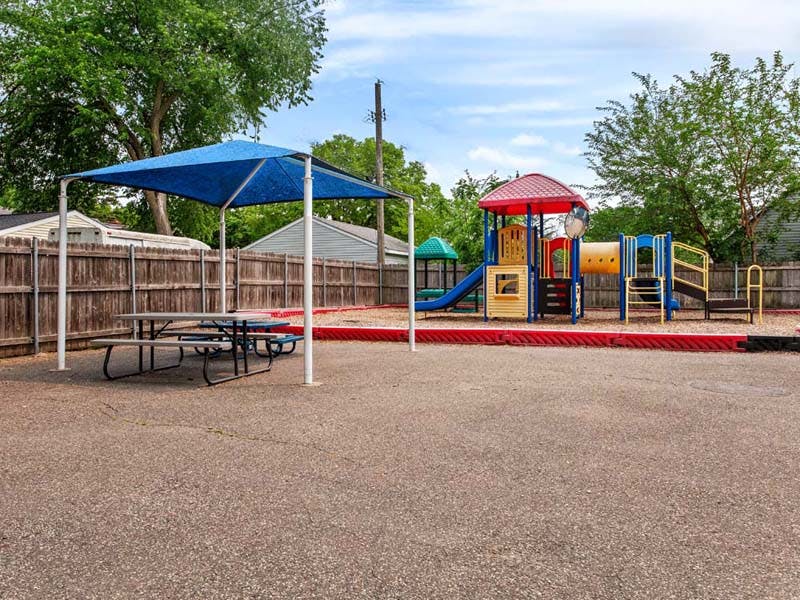 Playground area with a colorful play structure and shaded picnic tables
