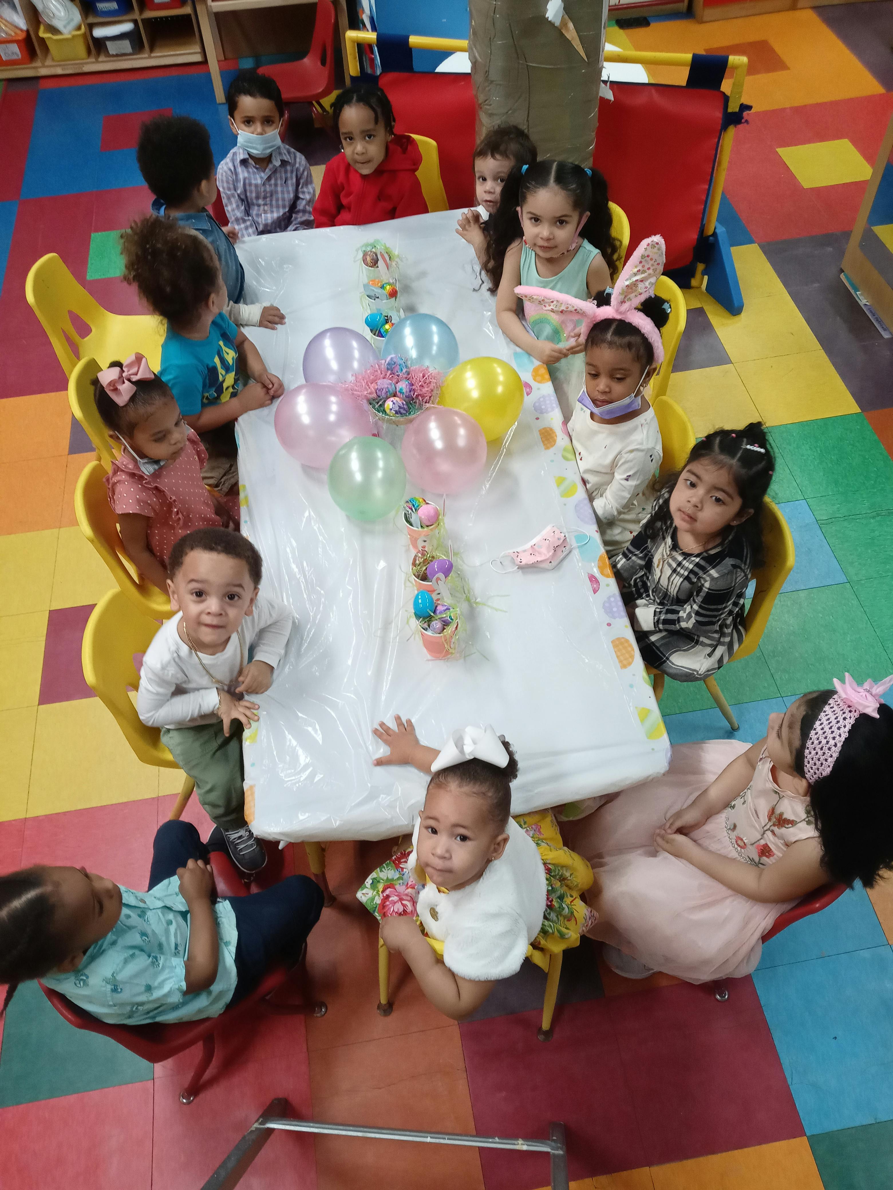 Children sitting around a table with balloons in a classroom