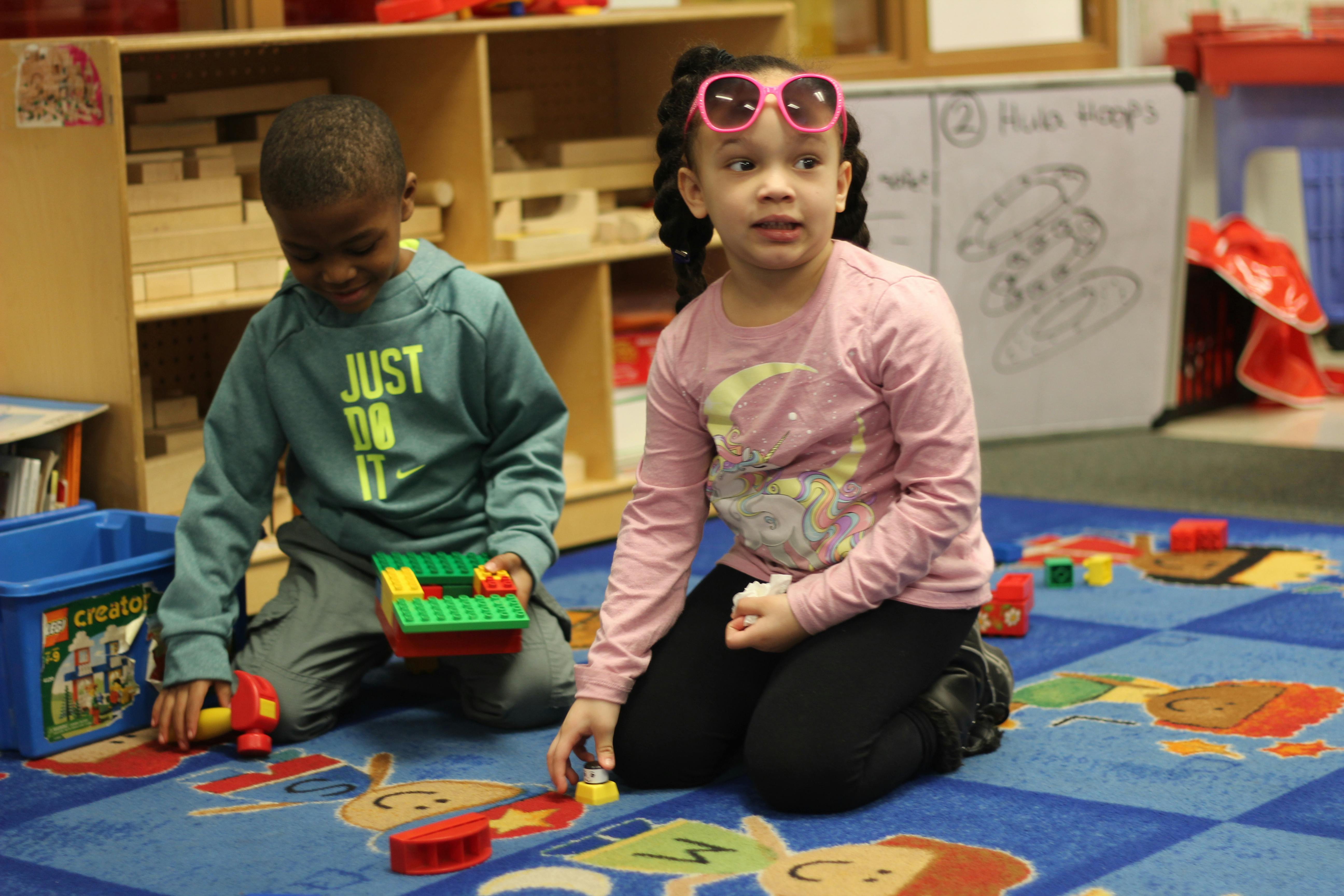 Two children playing with building blocks on a rug