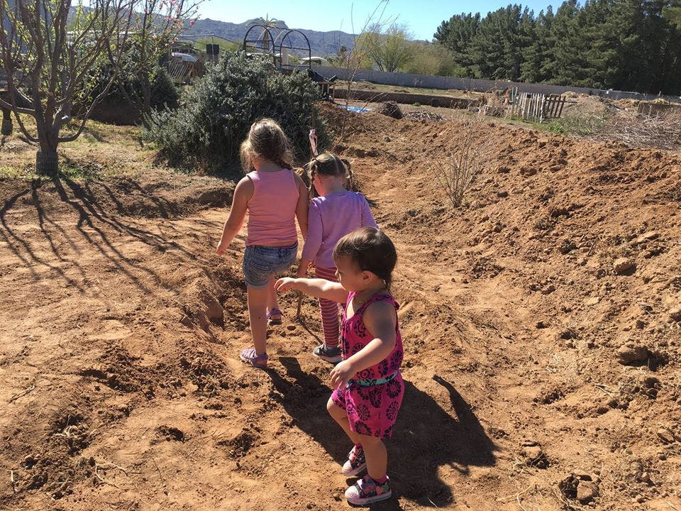 Three children walking on a dirt path
