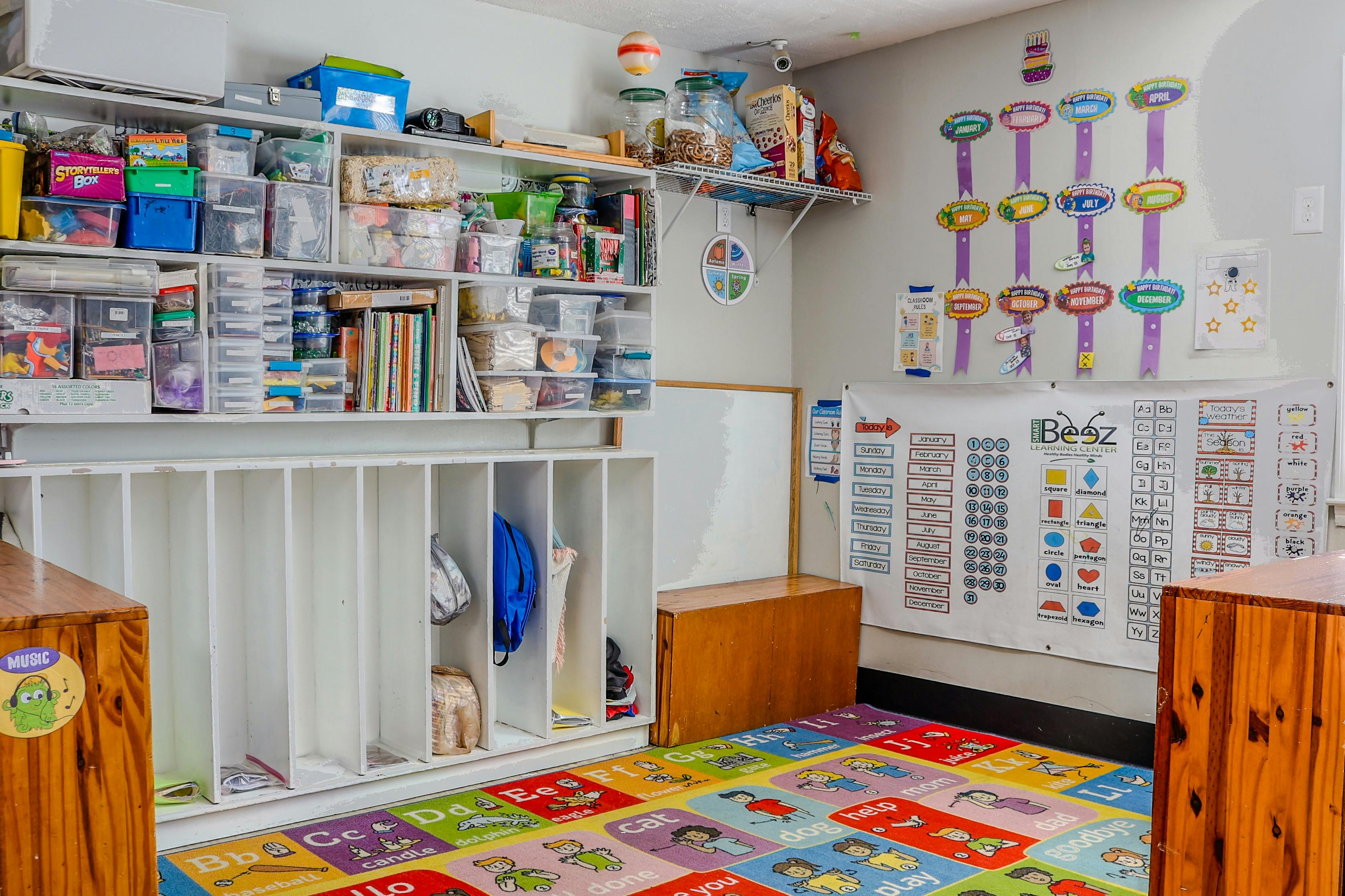 Classroom interior with storage shelving and an educational rug on the floor
