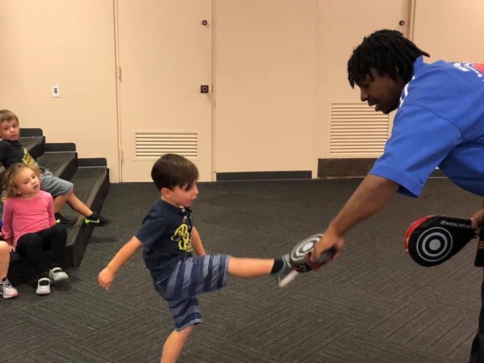 Adult holding kick pad for child kicking