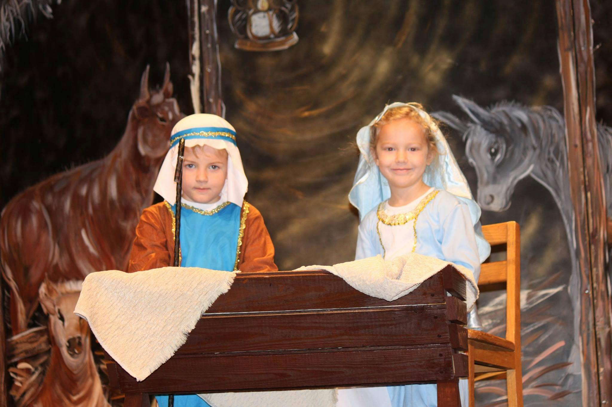 Two children in costumes behind a wooden manger