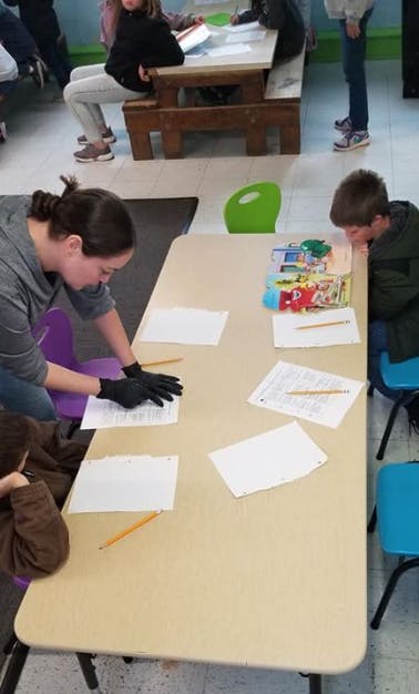 Person in black gloves working with papers on a table with children