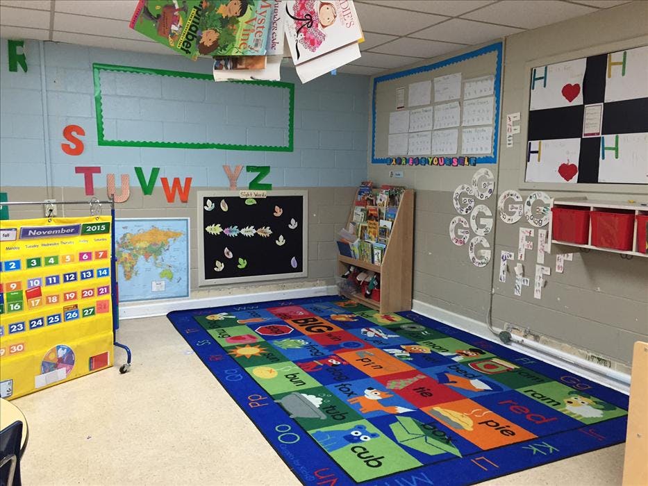 Classroom with an alphabet rug, calendar, map, and bookshelves