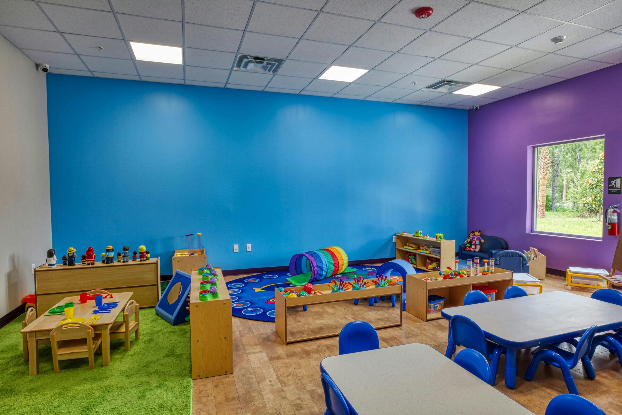 Children's playroom with colorful walls, tables, toys, and play tunnel