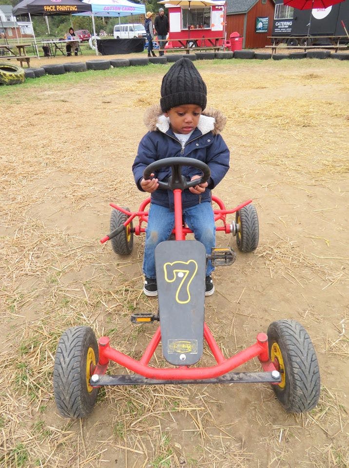 Child in a winter coat and hat riding a red pedal go-kart
