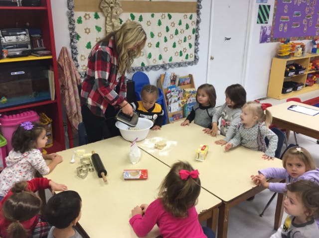 Person using a hand mixer with children watching in a classroom