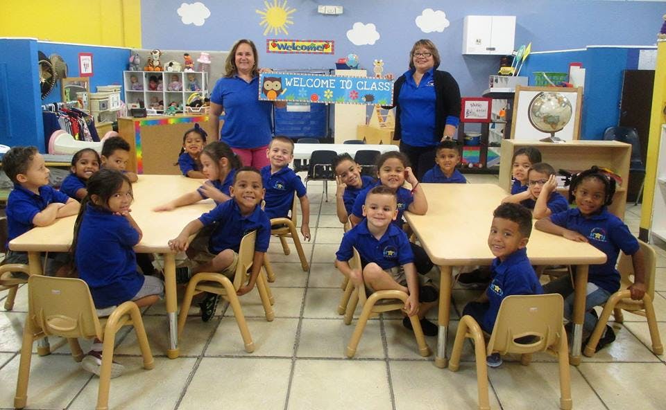 Two people and multiple children in a classroom