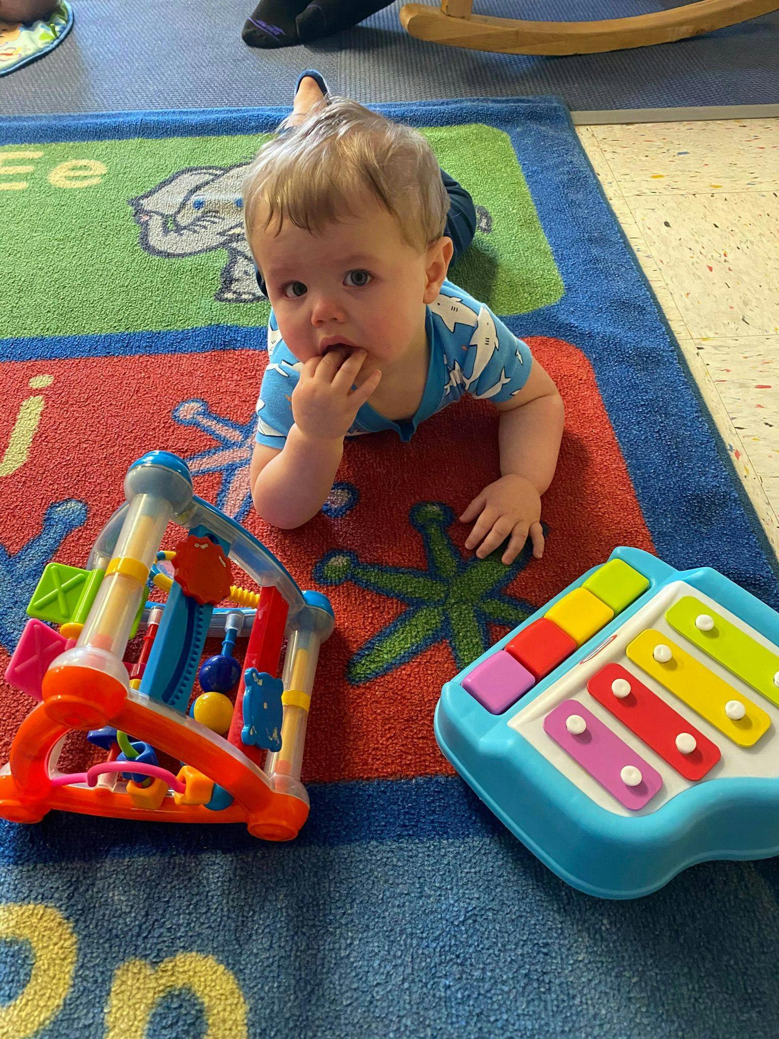 Child on a colorful rug with toys