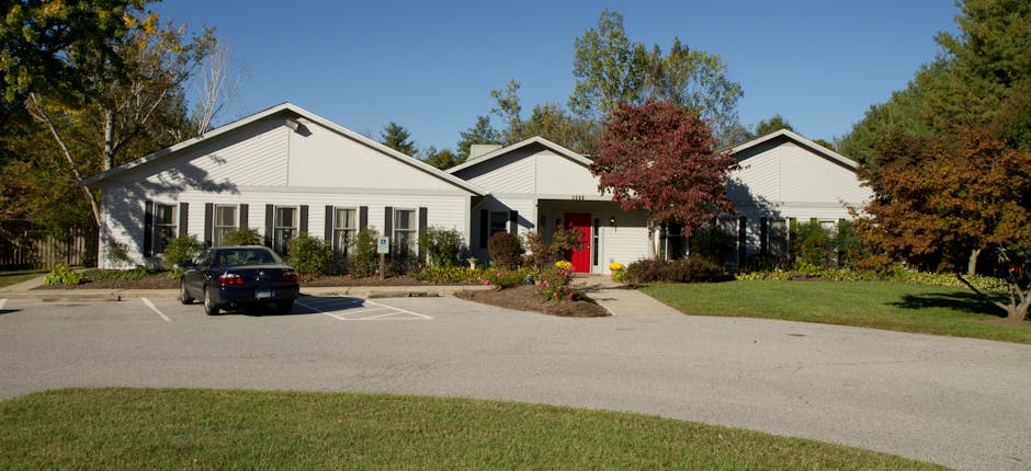 White building with a red door and a car in the parking lot