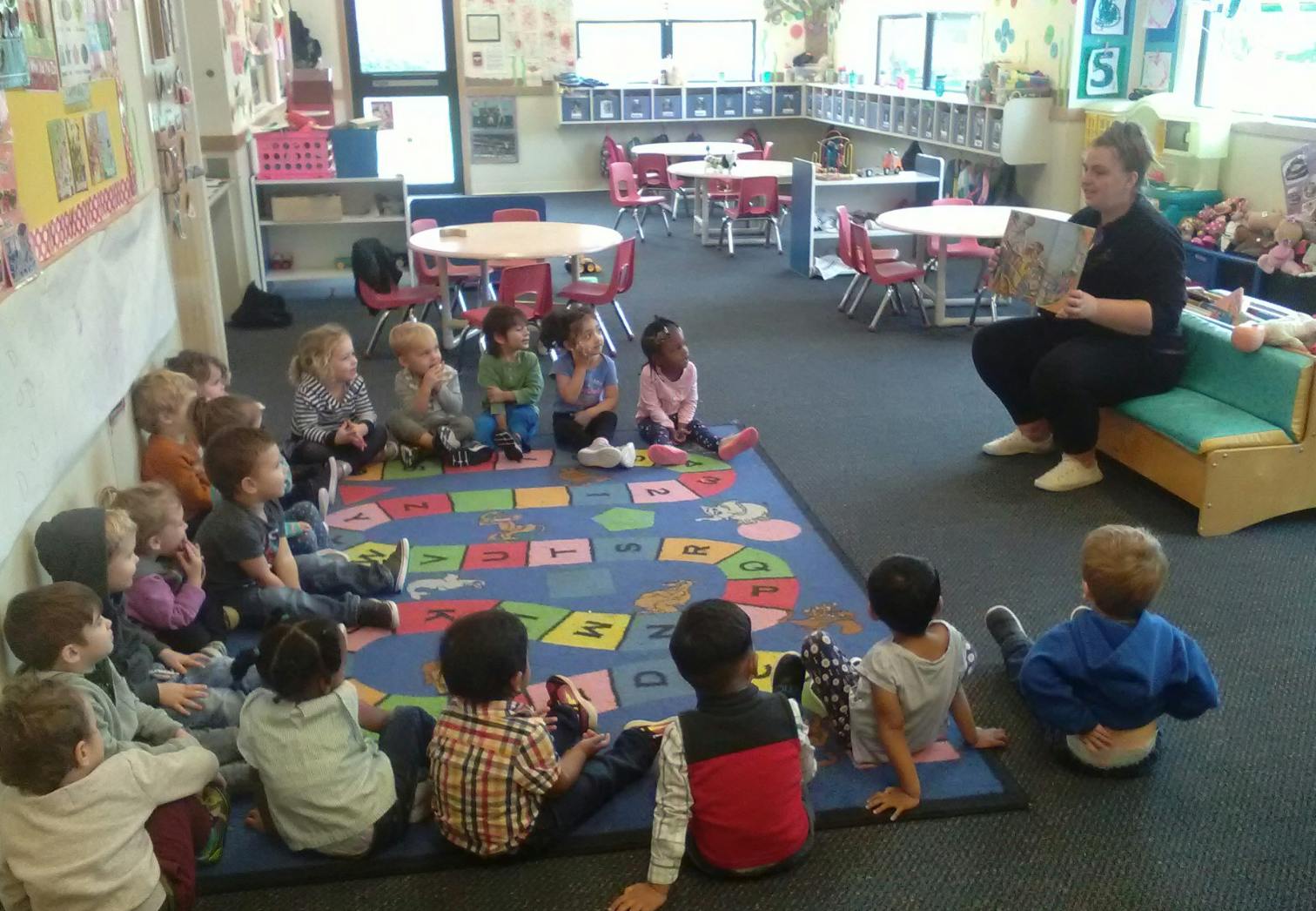 Person reading a book to children in a classroom