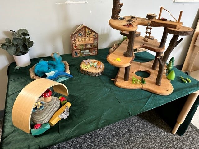 Table with wooden treehouse toy and other small toys