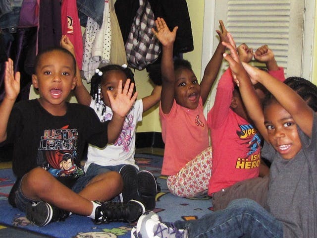 Group of children sitting on the floor with hands raised