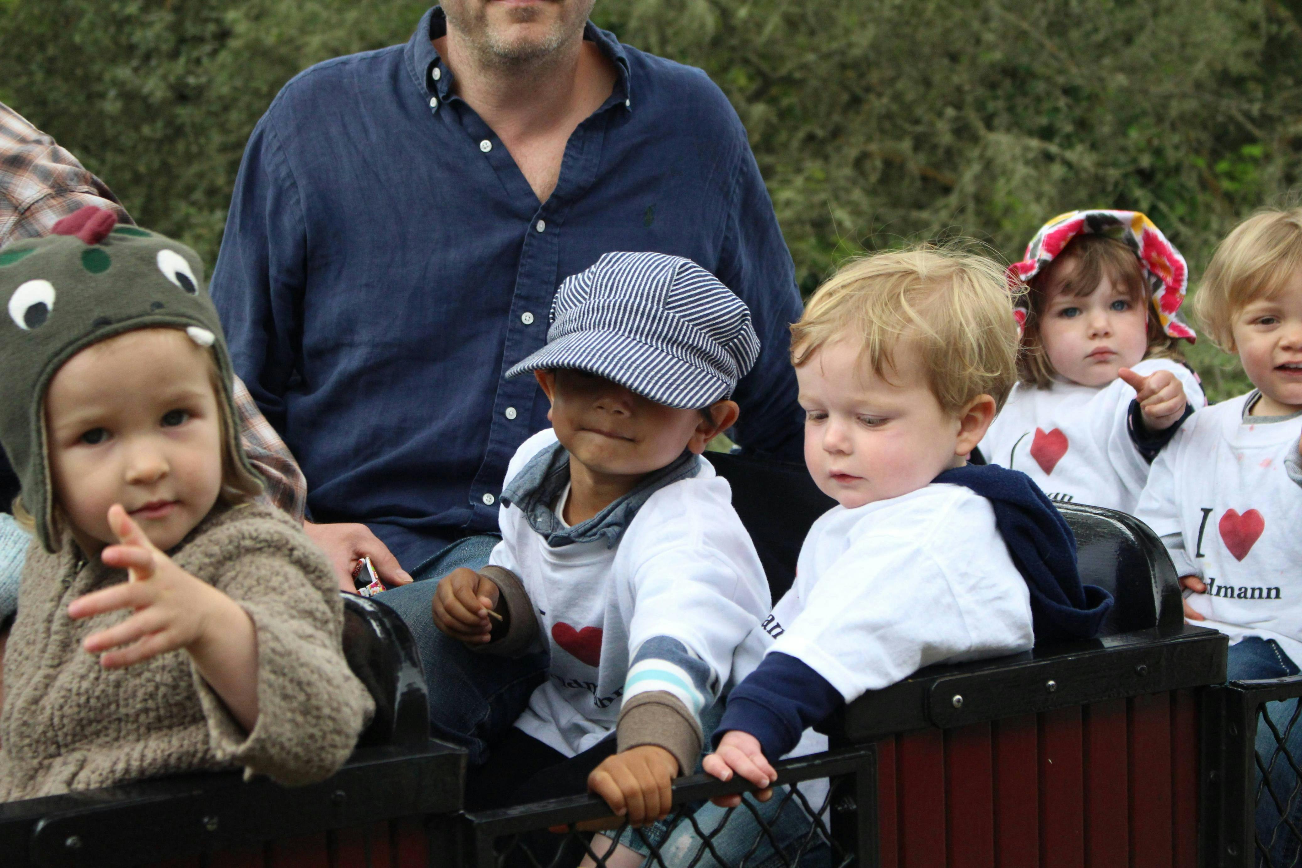 Adult and multiple children riding in a small train car