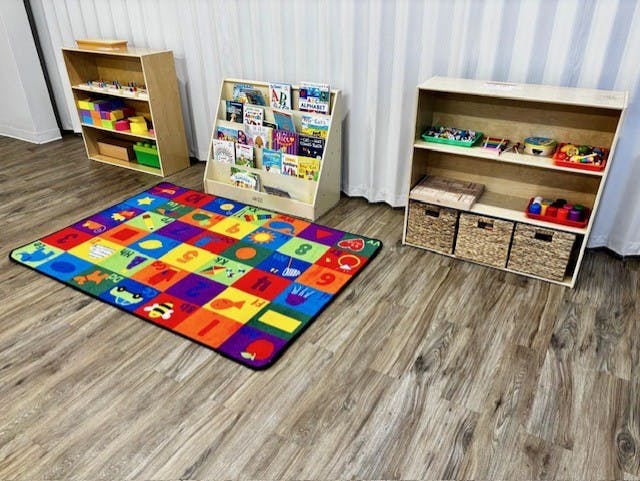 Colorful alphabet rug on a wooden floor with shelves of books and toys