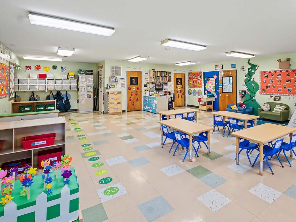 Empty classroom with small tables and chairs, and play areas