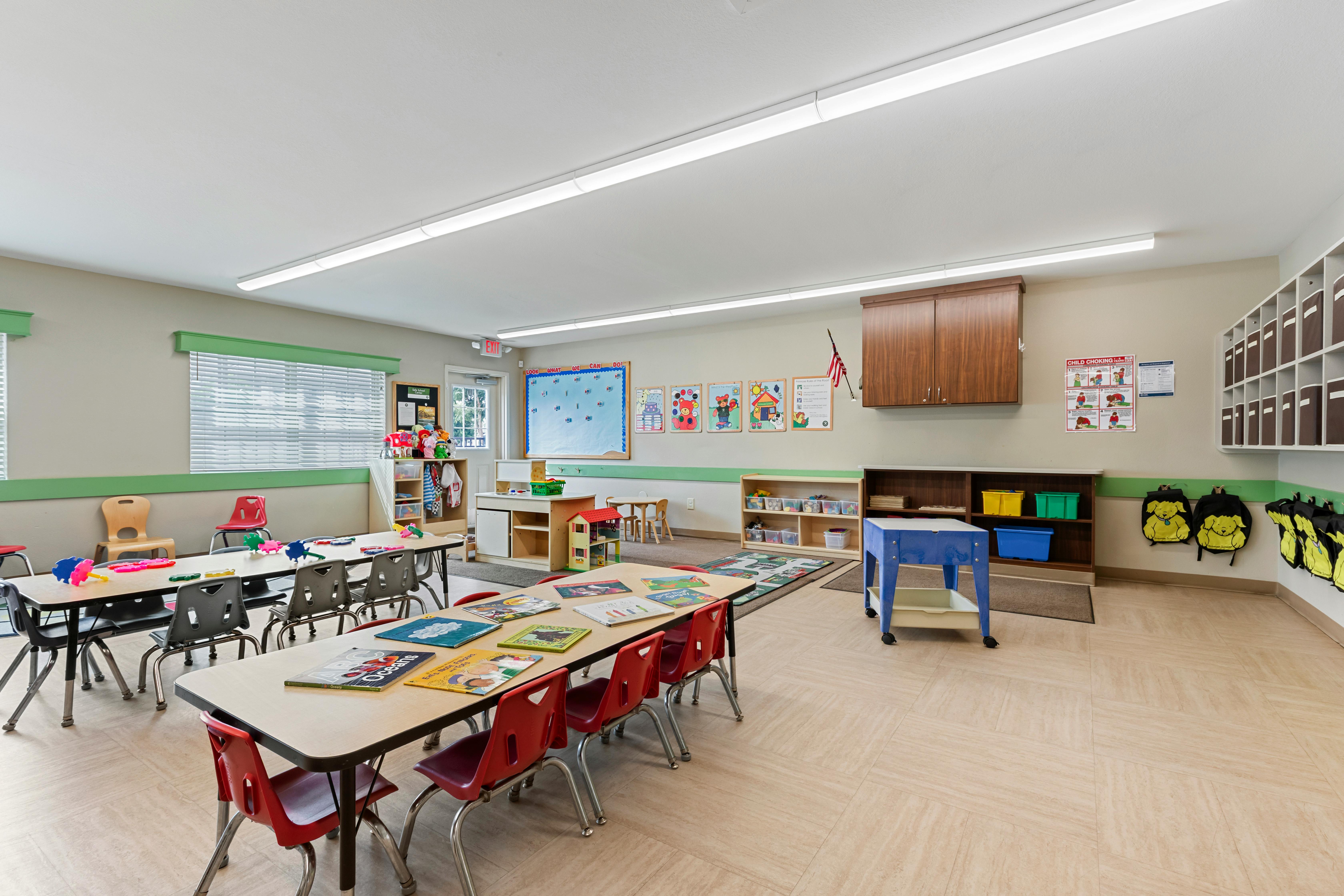 An empty early childhood classroom with multiple tables and chairs