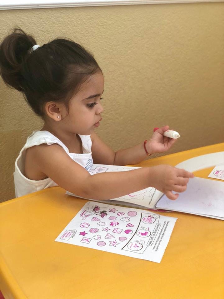 Child sitting at a table, looking at a book