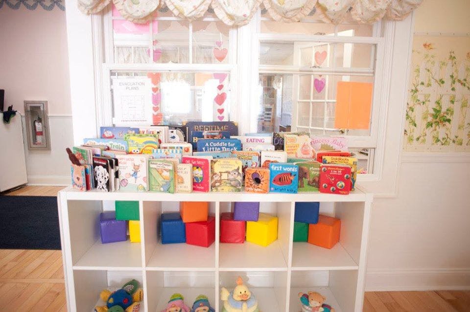 Books and colorful blocks on a white shelf in a classroom