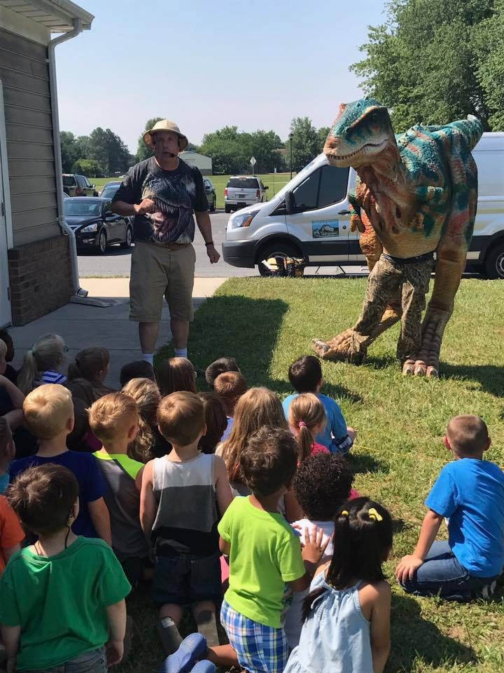 Person in a dinosaur costume and another person with a group of children