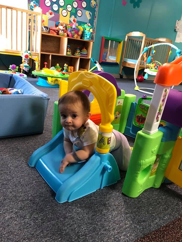 Child on a small blue slide in a play area