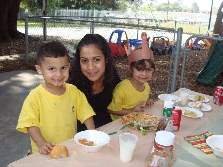 Person and two children at a table outdoors