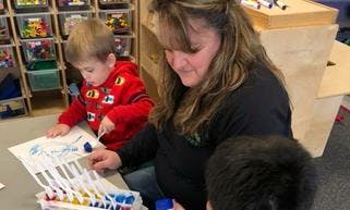 Adult and two children doing an art activity at a table