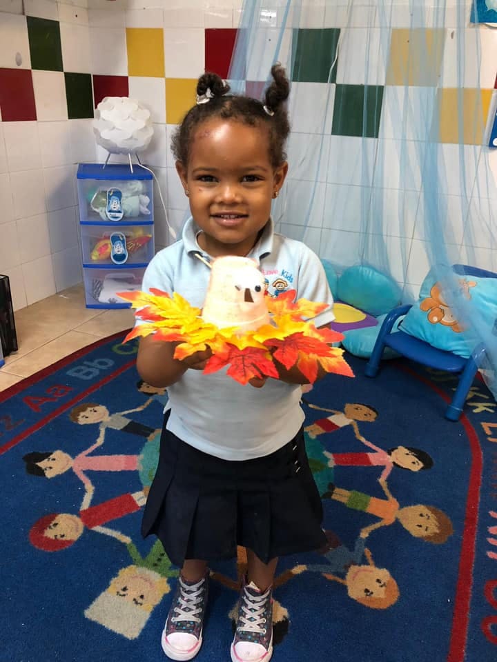 Child holding a craft with autumn leaves
