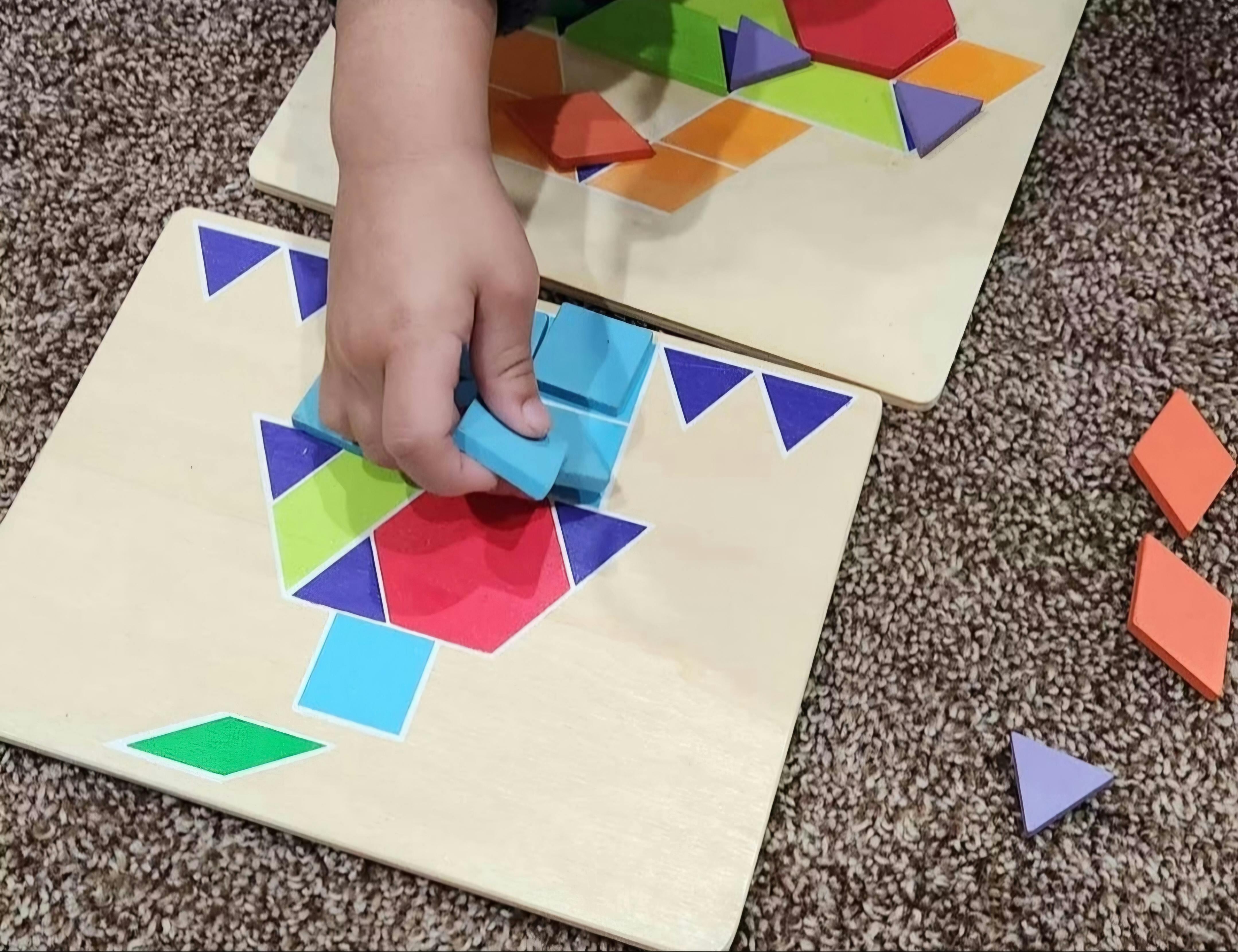 Child placing a wooden block into a geometric pattern puzzle