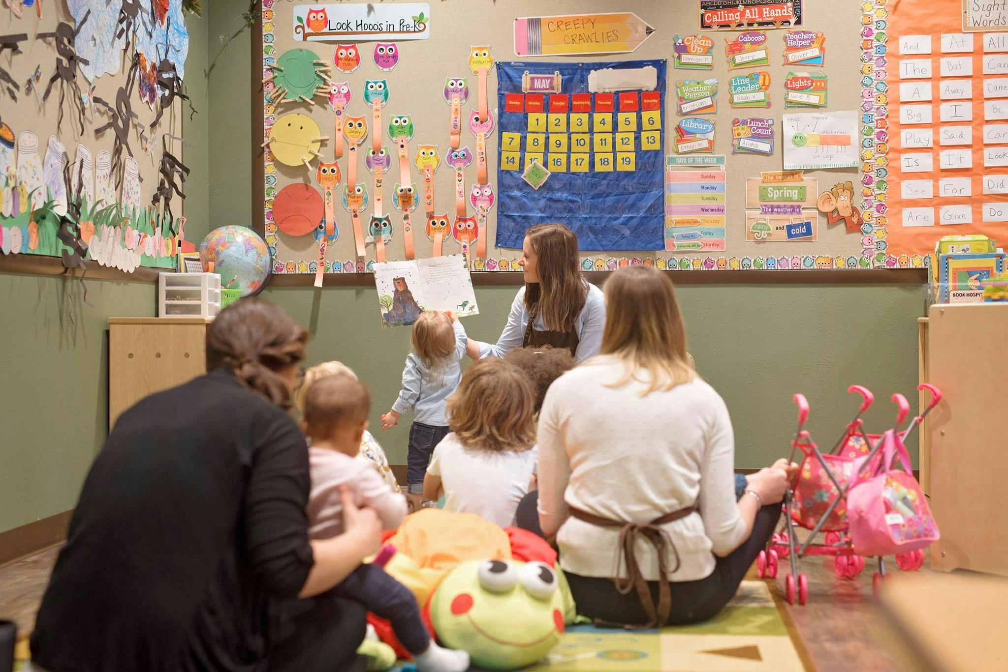 Adult reading a book to children in a classroom