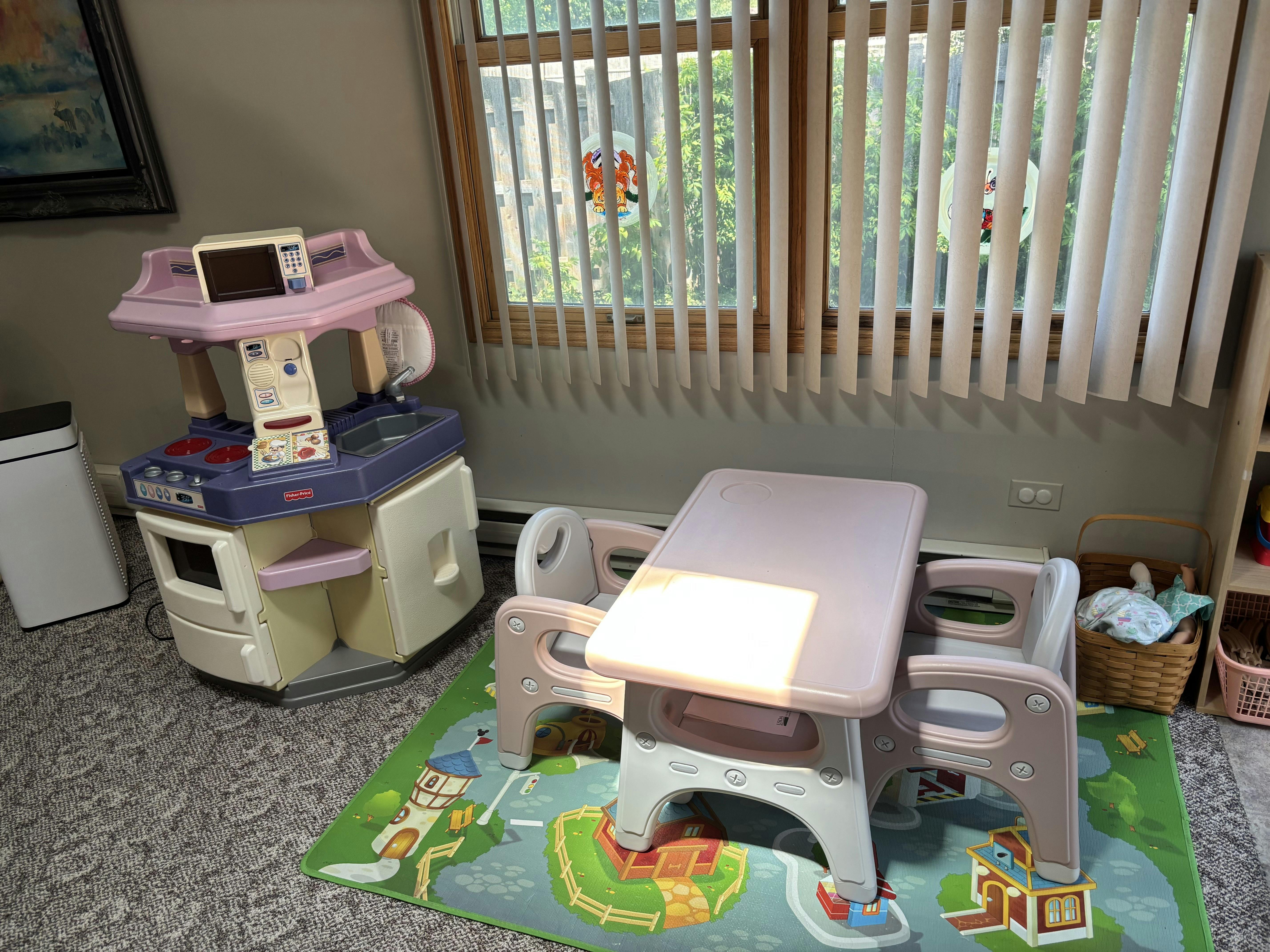Play kitchen and child-sized table and chairs on a decorative play mat