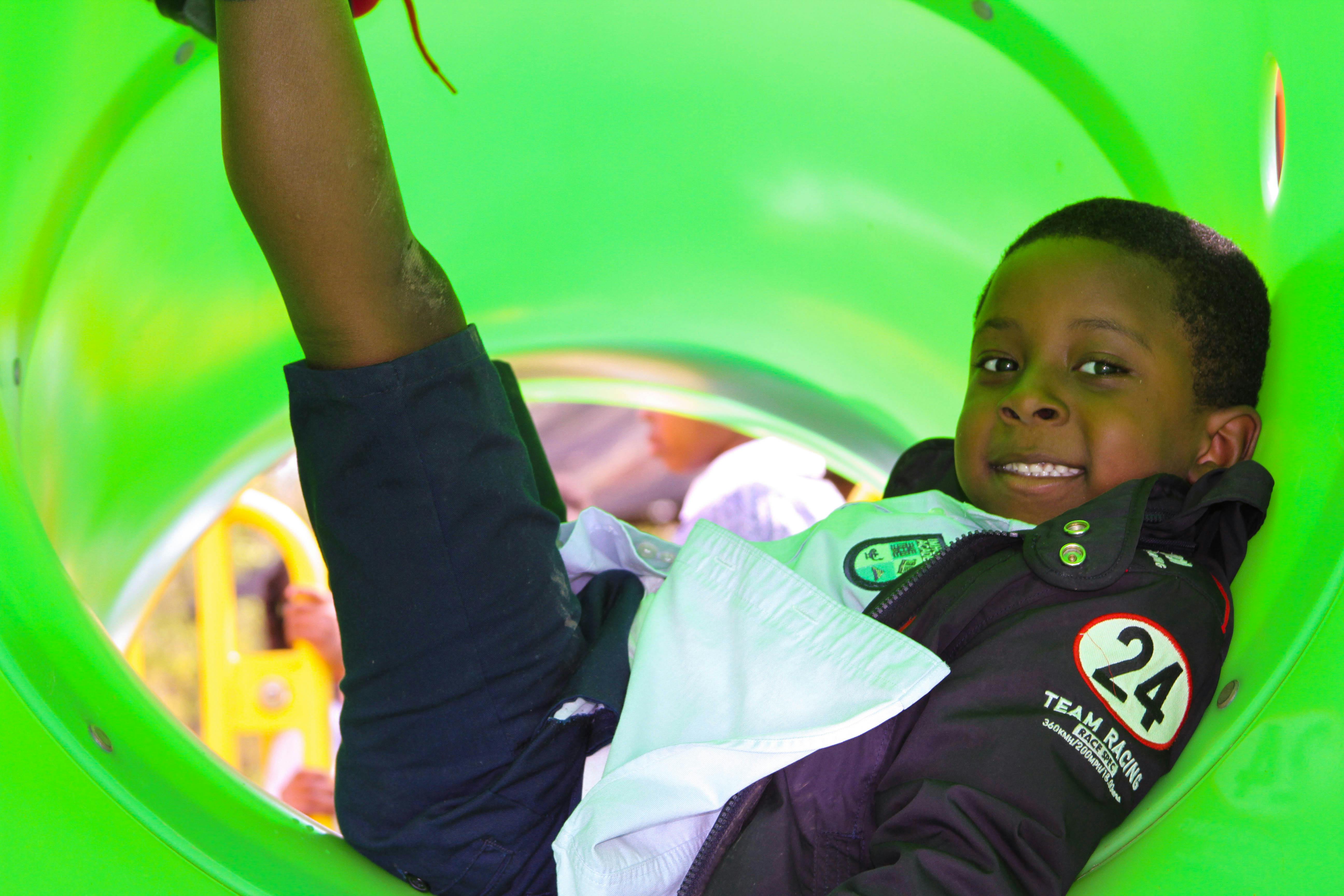 Child in a green playground slide