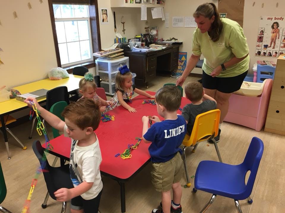 Adult supervising children at a table in a classroom