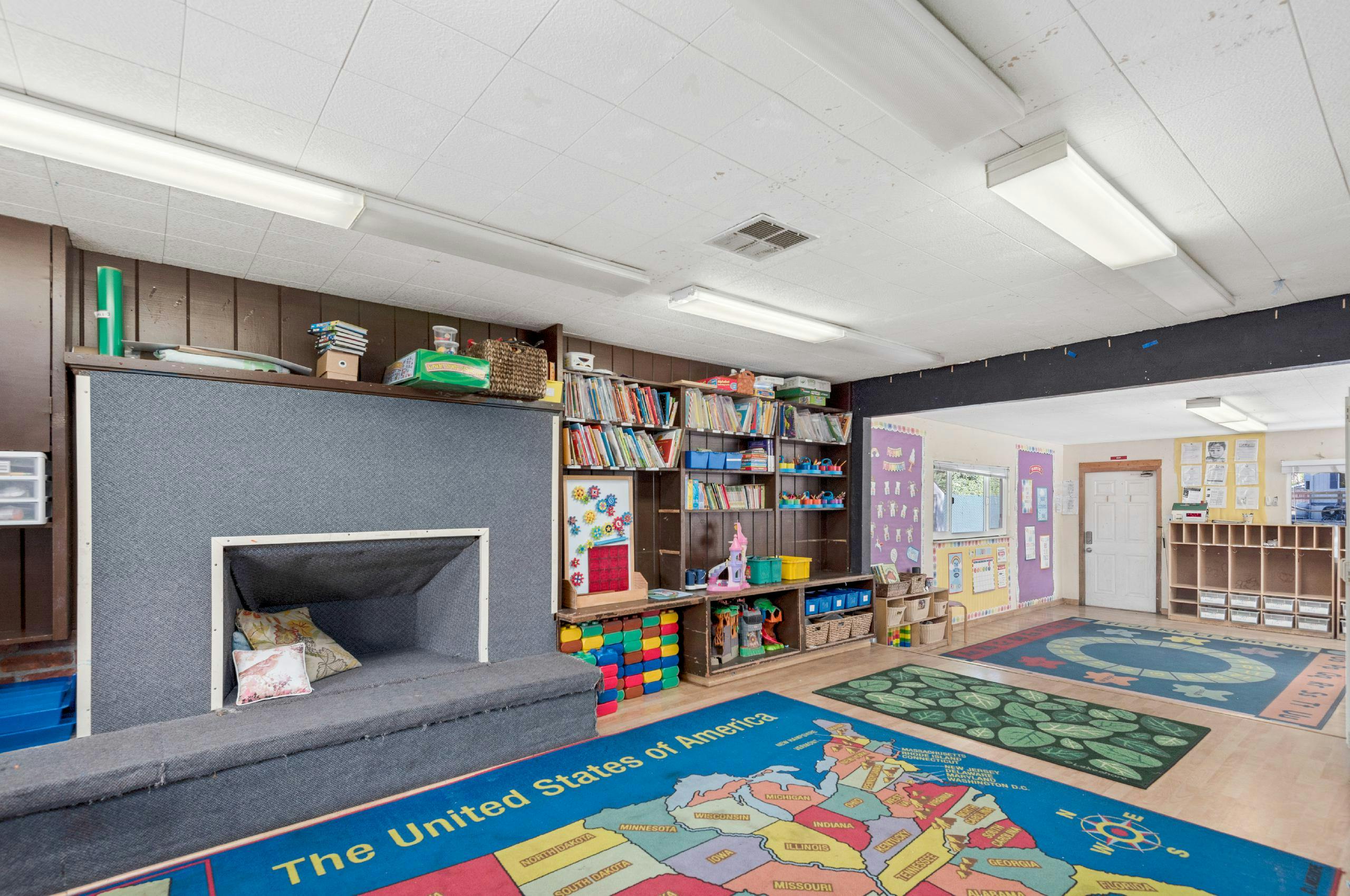 Classroom with a reading nook, bookshelves, and colorful rugs