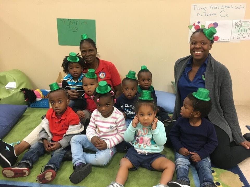 Two adults and several children wearing green hats