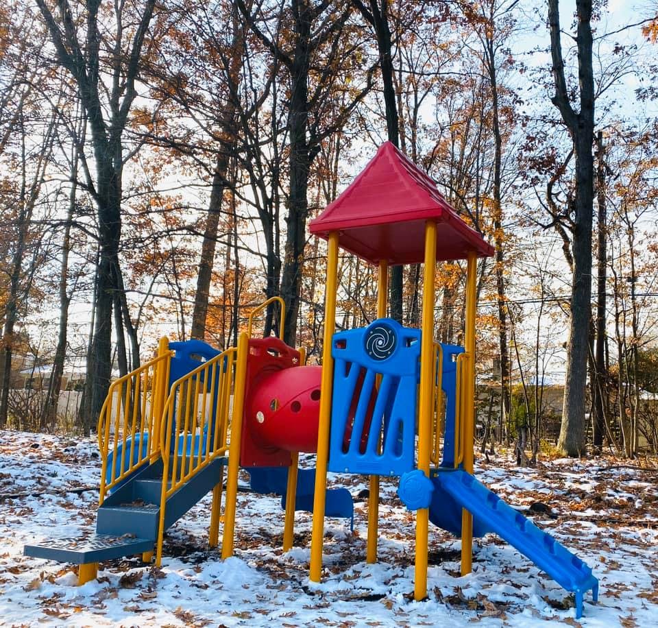 Playground equipment in a snowy, wooded area