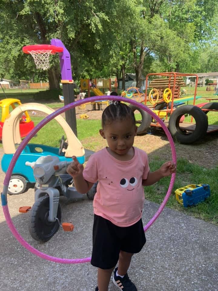 Child holding a hula hoop on a playground