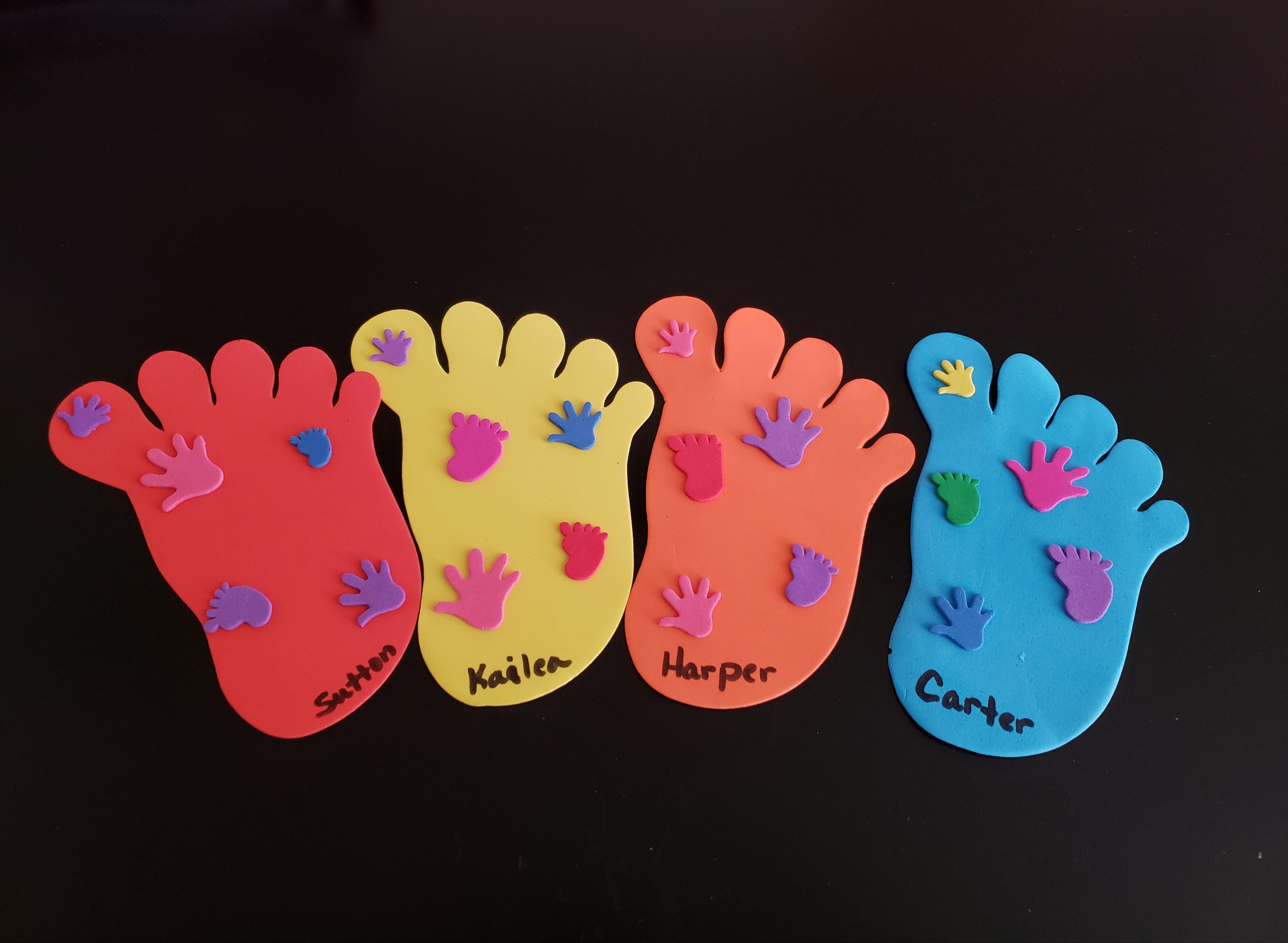 Four colorful foot cutouts with smaller hand cutouts and names written on them